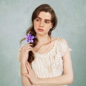 Elegant purple flower hair claw clip shown on a model with a minimalist backdrop