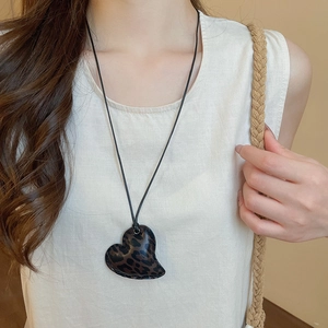 Close-up of heart-shaped leopard print pendant necklace with fine hand-stitched leather edge