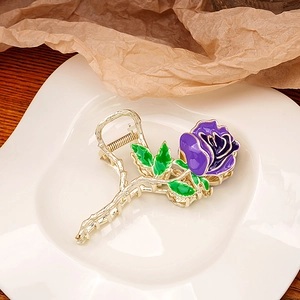 Detailed shot of a purple enamel rose hair claw with gold metal branch textures