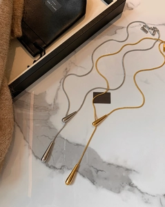 Detailed view of minimalist gold and silver teardrop pendant necklaces on marble