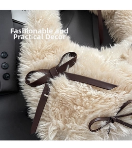 Macro shot of plush cream faux fur texture with a brown leather bow detail on bag