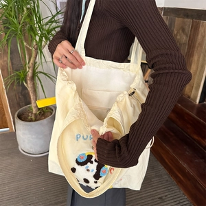 Detail view of the embroidered canvas tote featuring a plush animal patch and inner zip pocket