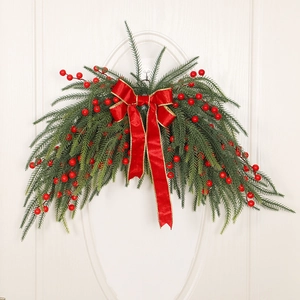 Christmas pine needle swag with red berries and a large festive golden-edged bow