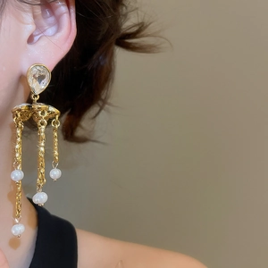Macro view of crystal flower earrings with long metallic tassels and white pearl drops
