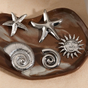 Polished silver starfish and sea shell brooch set on a ceramic tray for holiday styling