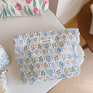 Gros plan détaillé d'une trousse à maquillage en coton fleuri avec étiquette brodée