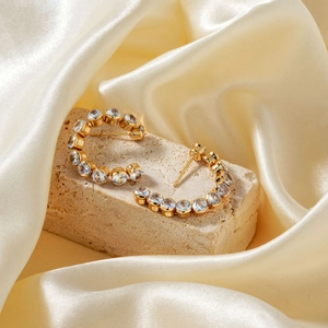 Elegant gold C-shaped hoop earrings with micro-pave cubic zirconia on satin backdrop