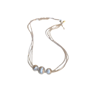 Layered silver multi-strand necklace featuring three brushed metallic round beads on a white background