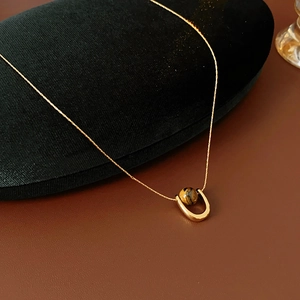 Macro view of gold titanium steel necklace with tiger eye stone pendant on black velvet