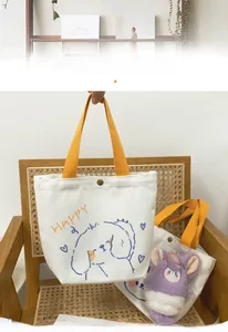 Detail of canvas tote bag with cartoon puppy print, yellow straps and snap button closure
