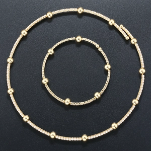 Macro shot of gold-plated jewelry set with zircon beads on a black textured background