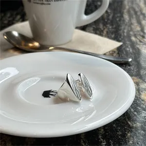 Polished 925 sterling silver minimalist rings on a ceramic plate with coffee set background