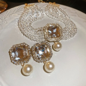 Close-up of vintage multilayer pearl necklace and earrings set with square rhinestones