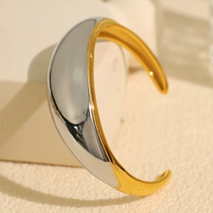 Polished two-tone gold and silver wide C-shape cuff bracelet on a minimalist stone