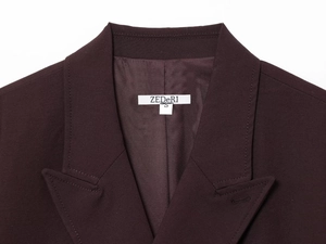Detailed close-up of notched lapel and branded neck label on dark purple blazer jacket