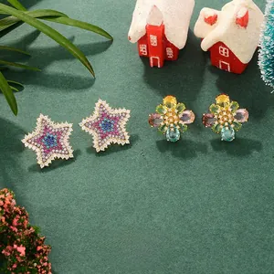Close-up of gold earrings with star and floral motifs set with colorful cubic zirconia