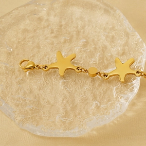 Detailed close-up of 18K gold-plated starfish bracelet with lobster clasp and sea shells
