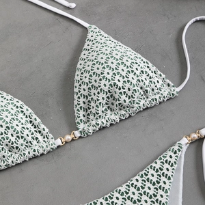 Detail of white crochet bikini top featuring gold metal rings and faux pearl accents