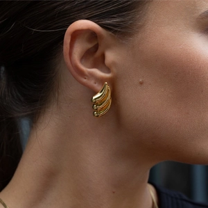 Close-up of a model wearing golden spiral drop earrings made of stainless steel