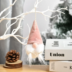 Pink Christmas gnome ornament with white beard and gold bow hanging on a festive tree