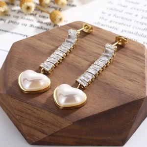 Macro shot of gold long tassel earrings with heart shell pendant and zircon stones