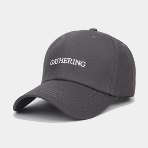 Gros plan sur la broderie GATHERING blanche sur une casquette en coton gris foncé