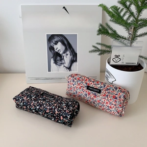 Close-up of floral corduroy pencil cases with merciparis label on a white desk