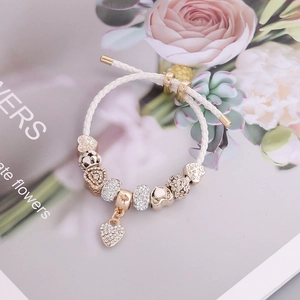 White woven leather bracelet with gold charms and sparkling crystal heart pendant
