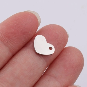 Macro shot of a small silver heart pendant for DIY jewelry making held in fingers