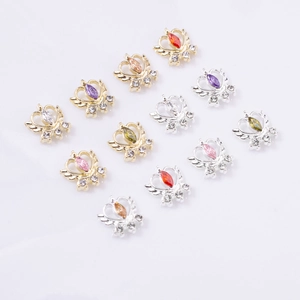 Macro view of winged crown nail charms with colorful zircon stones in gold and silver