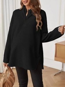 Detail of a black oversized maternity sweatshirt with half-zip collar and fleece texture