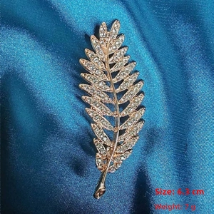 Detailed leaf-shaped brooch in gold finish with sparkling zircons, 6.3cm size