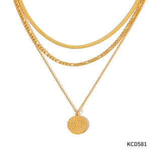 Détail d'un collier multicouche doré avec chaîne serpent et pendentif rond à texture fine