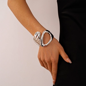 Close-up of abstract silver-toned asymmetric hollow cuff bracelet on a model's wrist