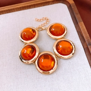 Dettaglio di un bracciale vintage dorato con cinque gemme tonde in resina arancione
