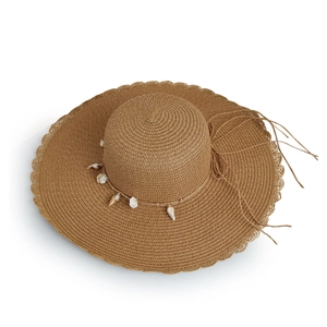 Detailed view of the straw beach hat featuring shell charms and a wavy wide brim