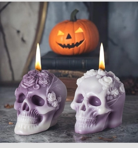 Detail of rose skull scented candle with lit wick against a gothic Halloween background