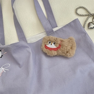 Detail of purple canvas tote with cartoon embroidery and brown plush bear charm