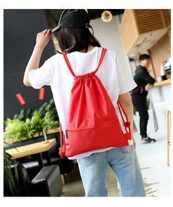 Red nylon drawstring backpack with honeycomb texture shown in a casual lifestyle setting