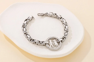 Detail of silver chain bracelet with pavé-set round pendant showing a boy and girl motif