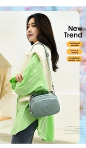 Model wearing a multi-compartment nylon crossbody bag in Morandi blue with adjustable strap