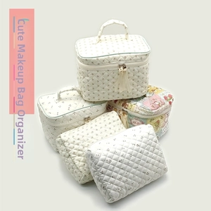 Detail view of quilted floral makeup bags with satin zipper pulls and storage variety