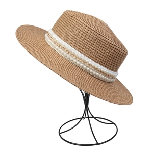 Detail of khaki straw hat with white pearl beads and gold metal chain decoration