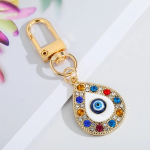 Golden keychain with blue evil eye pendant and colorful rhinestones on a clean background