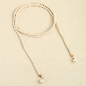 Detail of minimalist beige cord belt featuring golden metal tips and elegant round pearls