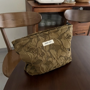 Detailed view of floral relief texture and fabric label on a green cosmetic bag