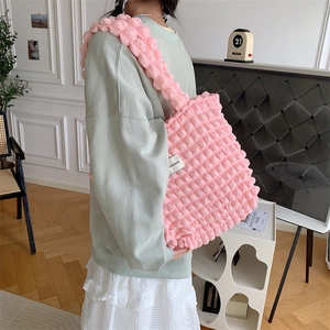 Detailed view of pink bubble texture shoulder bag with brand label and large capacity