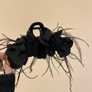 Detail of elegant black fabric flower hair claw clip with delicate feather accents