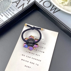 Detail of purple crystal flower hair tie with black elastic rope and gold metal tips