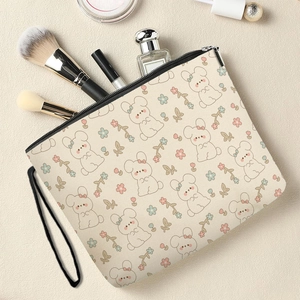 Cute bunny floral canvas makeup bag with zipper and wrist strap on a vanity desk